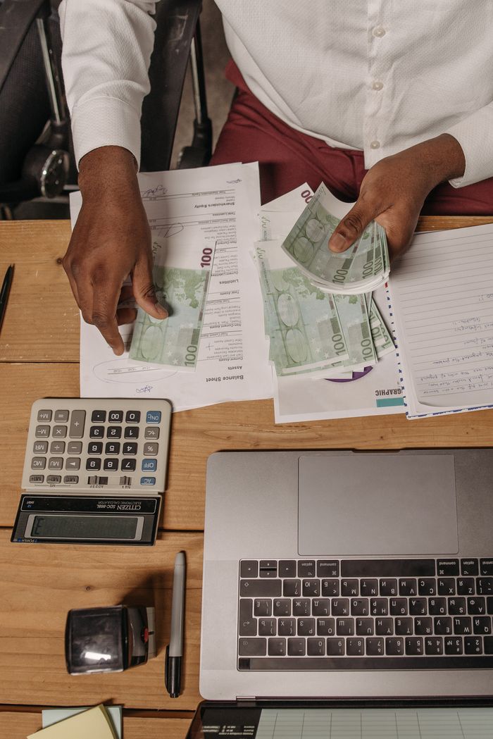 The Art of Drawing Readers In: Your attractive post title goes here An overhead view of a professional counting cash and using a calculator to manage finances on a wooden desk.